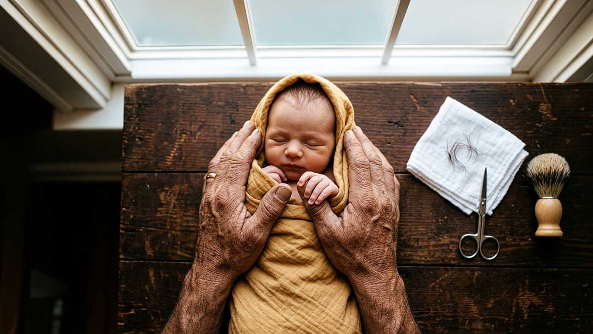 Aqiqah in Islam father's hands holding newborn in golden cloth