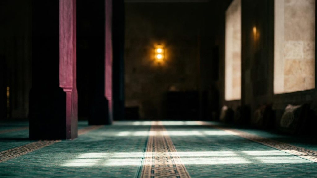 A still-life of an empty prayer mat with light falling straight across it, illustrating the Dua After Rising from Ruku.