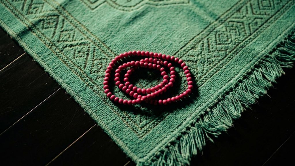 A still-life of prayer beads resting on a mat after the prayer has finished, illustrating the Dua After Salah.