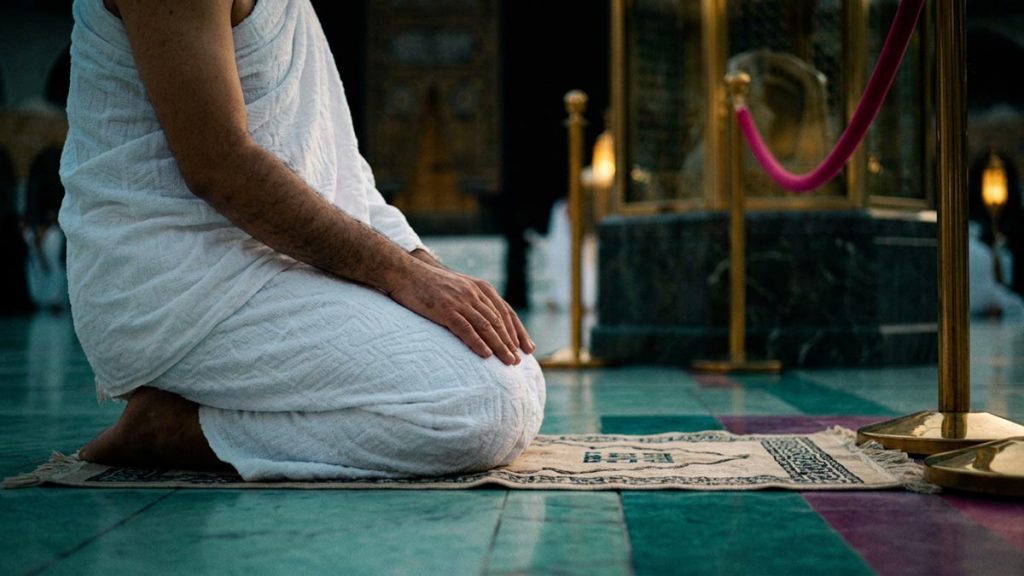 Close view of a Muslim pilgrim's hands and the marked place of prayer during the Dua at Maqam Ibrahim.