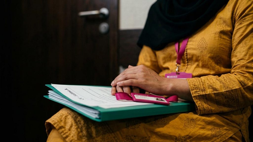 Close view of a Muslim woman's hands and the folder of documents and a name badge during the Dua Before an Interview.