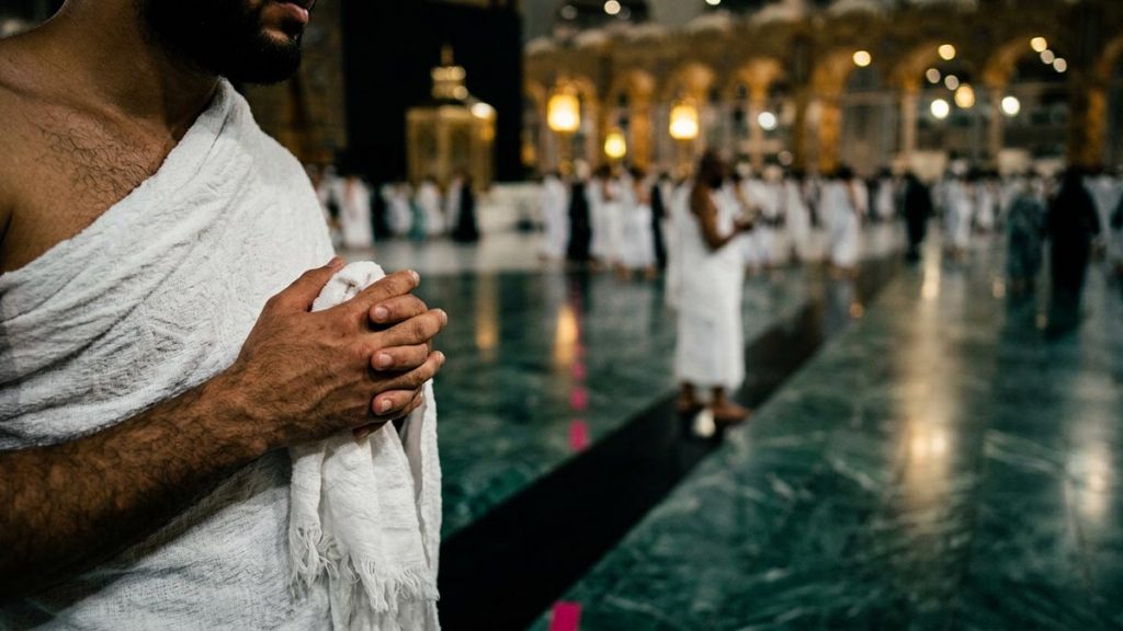 Close view of a Muslim pilgrim's hands and the polished marble floor of the circuit path around the courtyard during the Dua During Tawaf.
