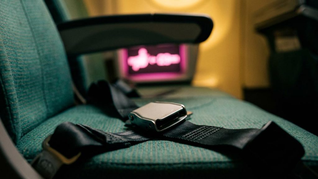A still-life of a fastened seatbelt and an illuminated seatbelt sign in an aircraft cabin, illustrating the Dua During Turbulence.