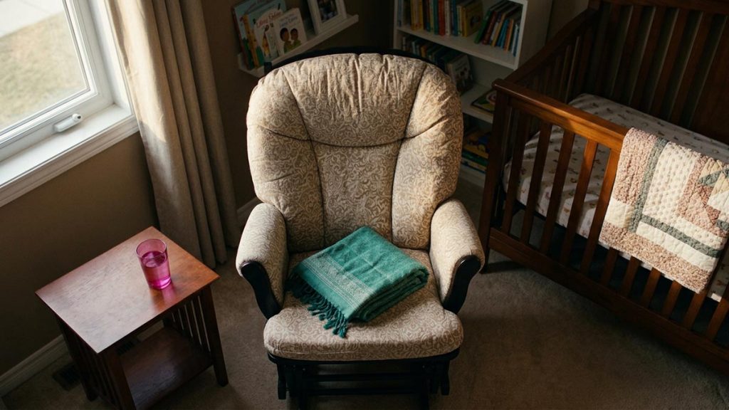A still-life of a nursing chair with a folded shawl and a glass of water beside it, illustrating the Dua for Breastfeeding Mothers.