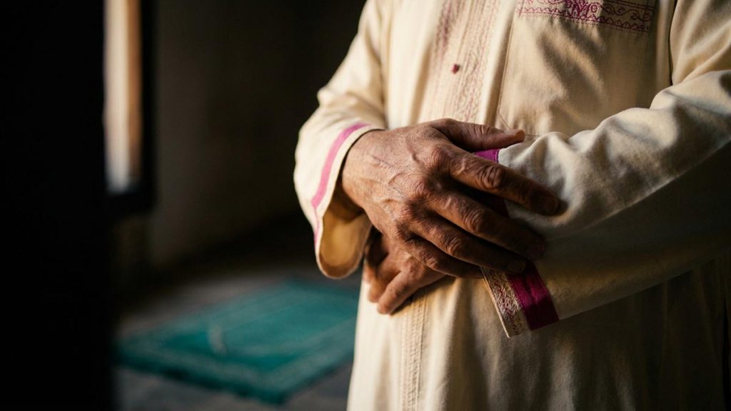 Close view of a Muslim man's hands and the bare room during the Dua for Concentration in Salah.