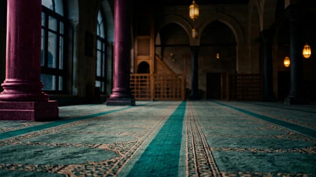 A still-life of a prayer hall in unusual half-light during an eclipse, illustrating the Dua for Eclipse Prayer.