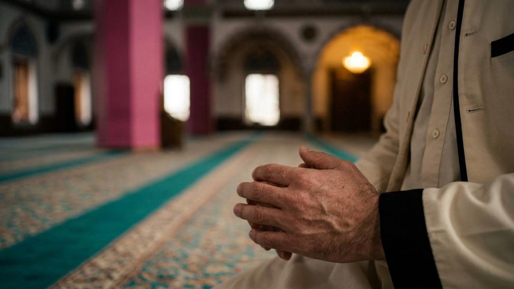 Close view of a Muslim man's hands and the prayer hall carpet during the Dua for Firmness in Faith.
