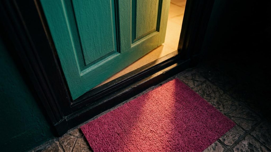A still-life of a held-open door with light spilling through onto the step, illustrating the Dua for Good Character.