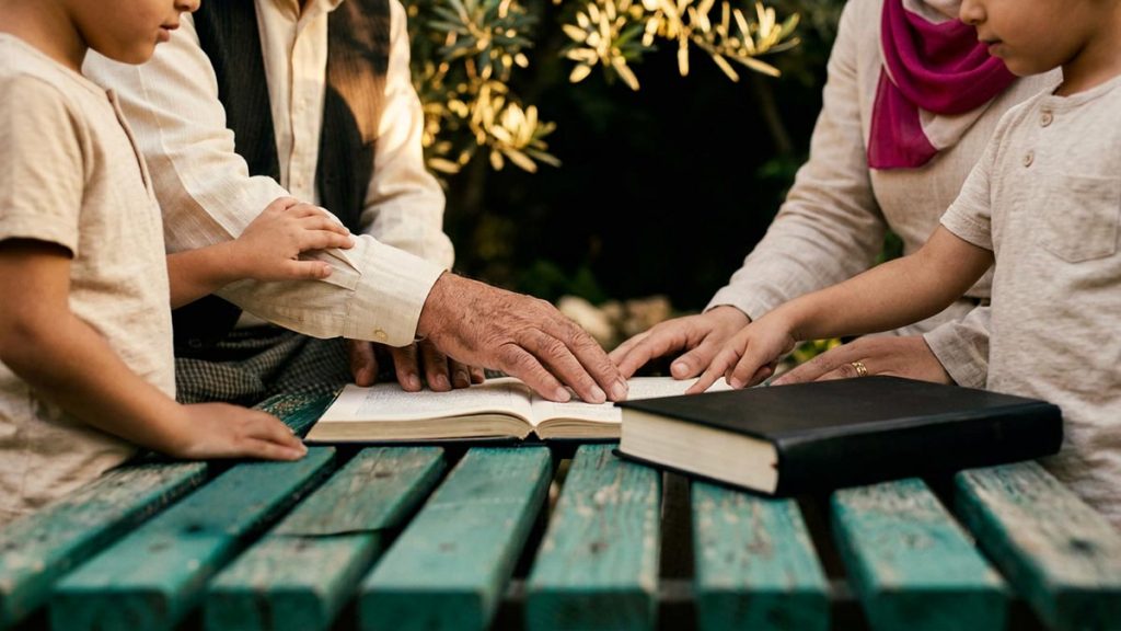Close view of a Muslim family's hands and the storybook and two small pairs of shoes during the Dua for Grandchildren.
