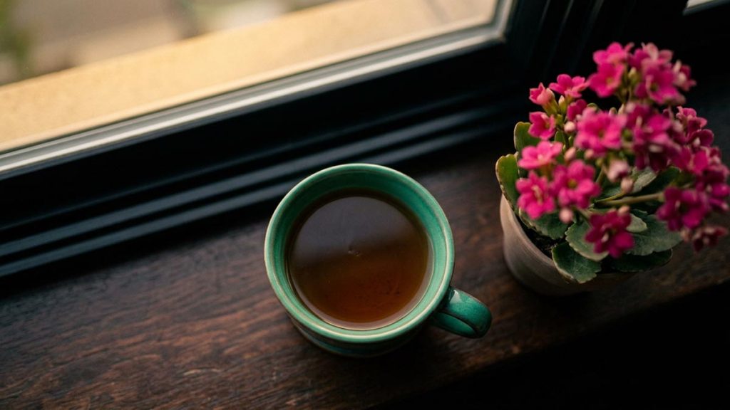 A still-life of a single cup of tea on a windowsill in an empty room, illustrating the Dua for Loneliness.