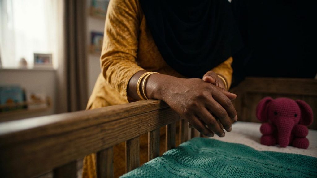 Close view of a Muslim woman's hands and the wooden cot during the Dua for Pregnancy.