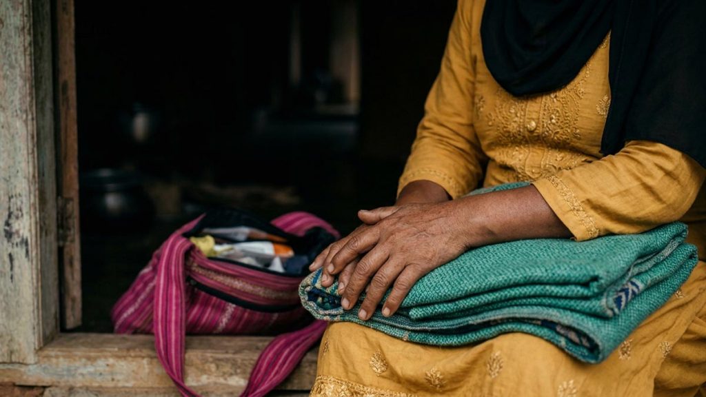 Close view of a Muslim woman's hands and the folded blanket and a packed emergency bag during the Dua for Safety During Conflict.