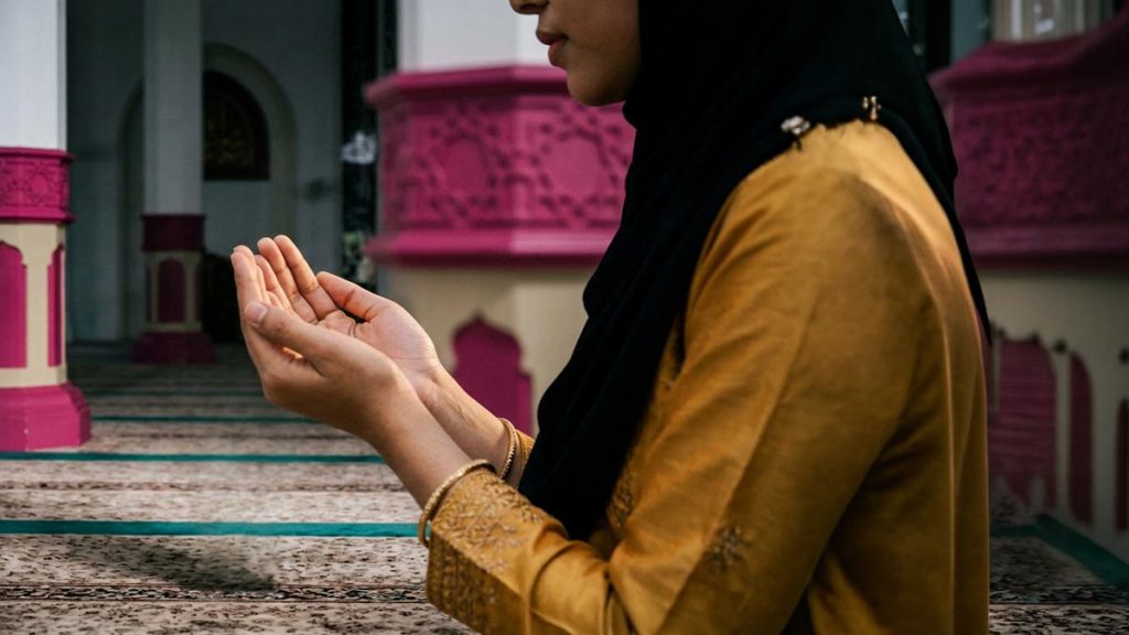 Close view of a Muslim woman's hands and the prayer hall during the Dua for Steadfastness.