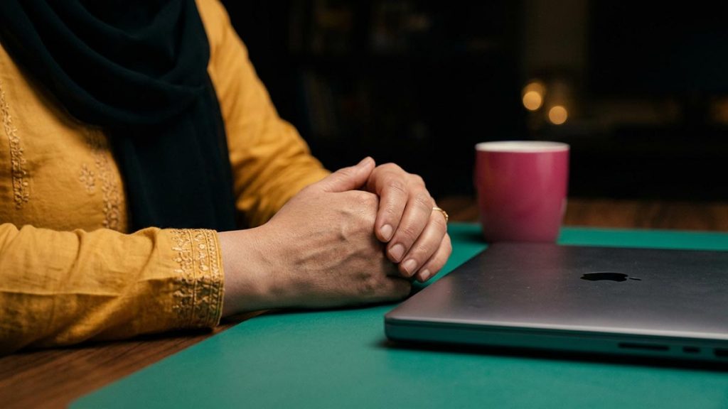 Close view of a Muslim woman's hands and the closed laptop during the Dua for Stress.