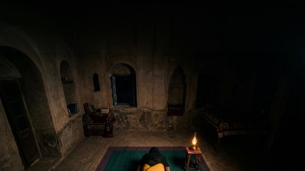 A Muslim woman seen from behind on a prayer mat in the depth of the night, reflecting the Dua for Tahajjud.