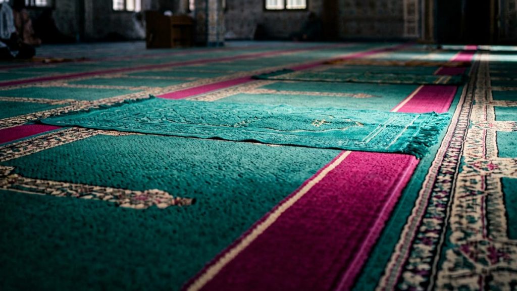 A still-life of a prayer mat marked with the place of prostration in soft light, illustrating the Dua in Sujood.