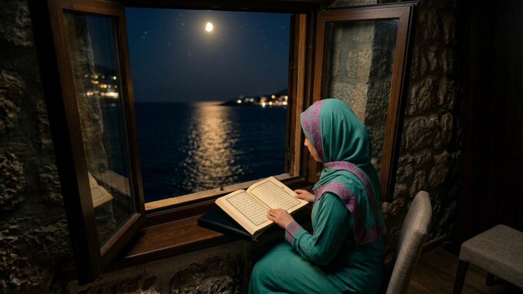A Muslim woman seen from behind at a window overlooking the sea at night, reflecting the Dua of Prophet Yunus.