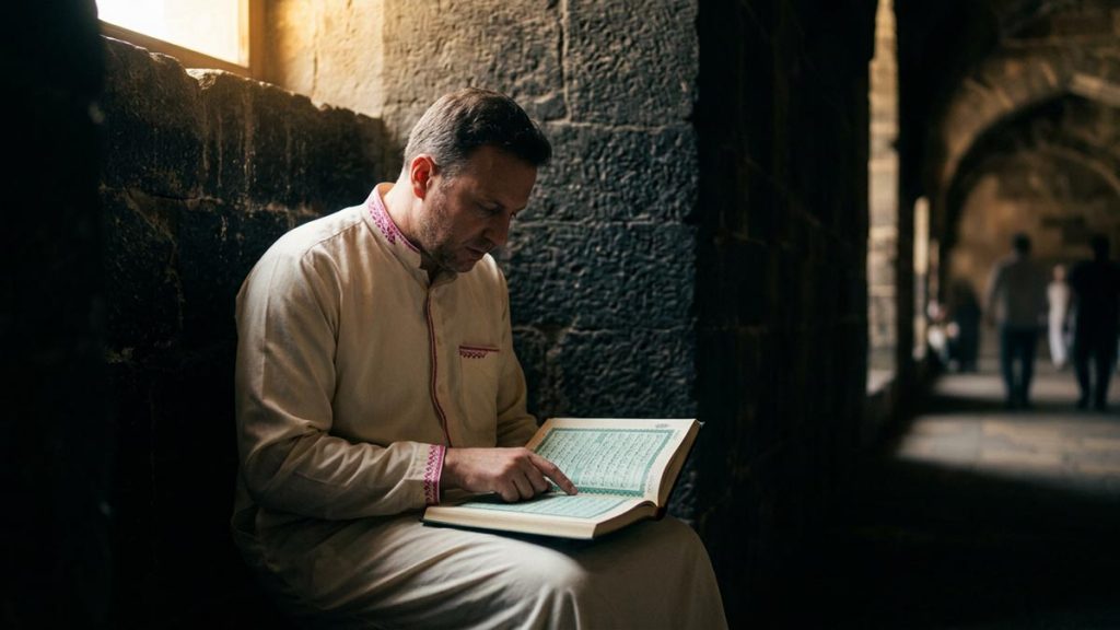 A Muslim man in a sheltered stone alcove with the Quran open, an opening scene for the Dua of the People of the Cave.