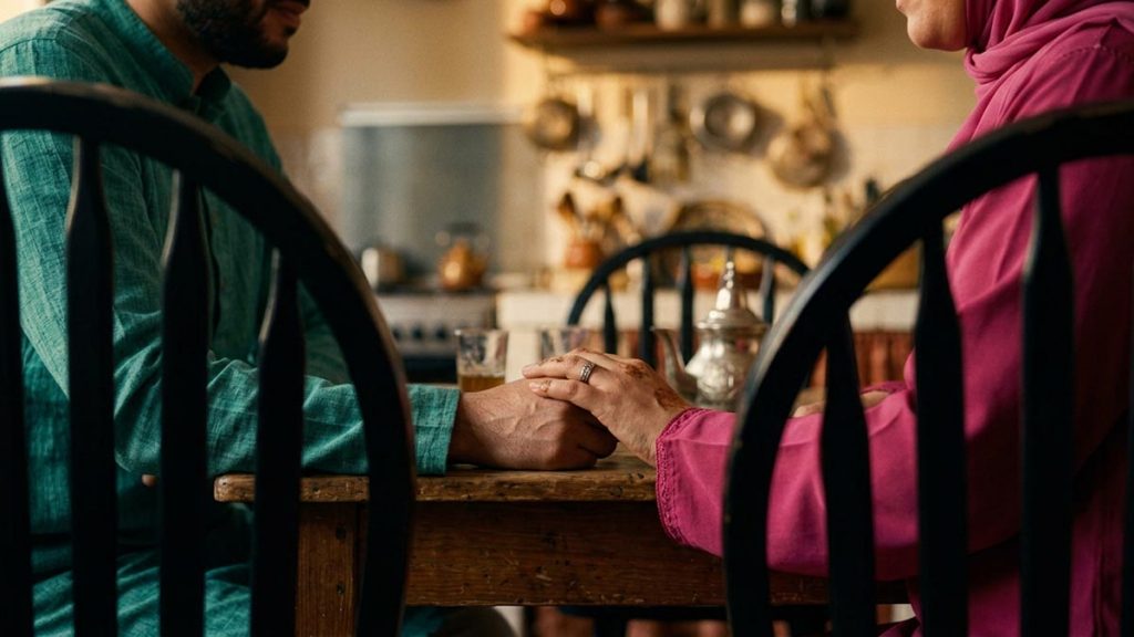 Close view of a Muslim family's hands and the two chairs drawn close during the Dua to Strengthen Marriage.