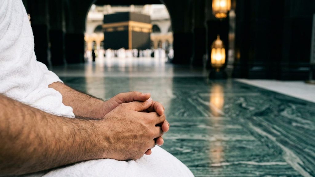 Close view of a Muslim pilgrim's hands and the marble courtyard of the Sacred Mosque seen during the Dua Upon Seeing the Kaaba.