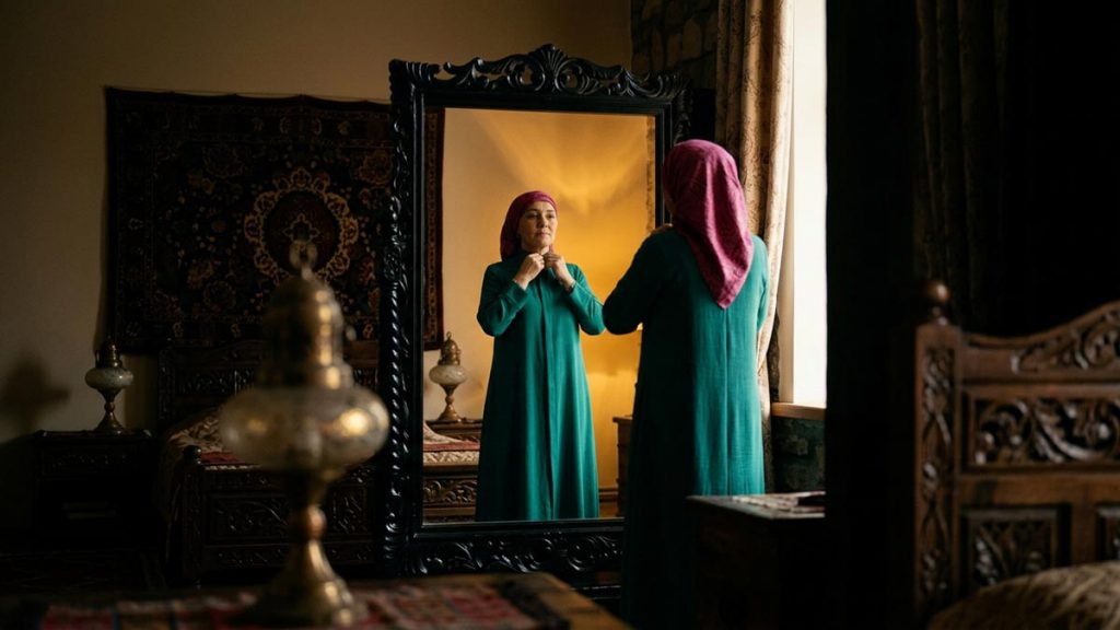 A Muslim woman before a framed mirror in a softly lit room, an opening scene for the Dua When Looking in the Mirror.