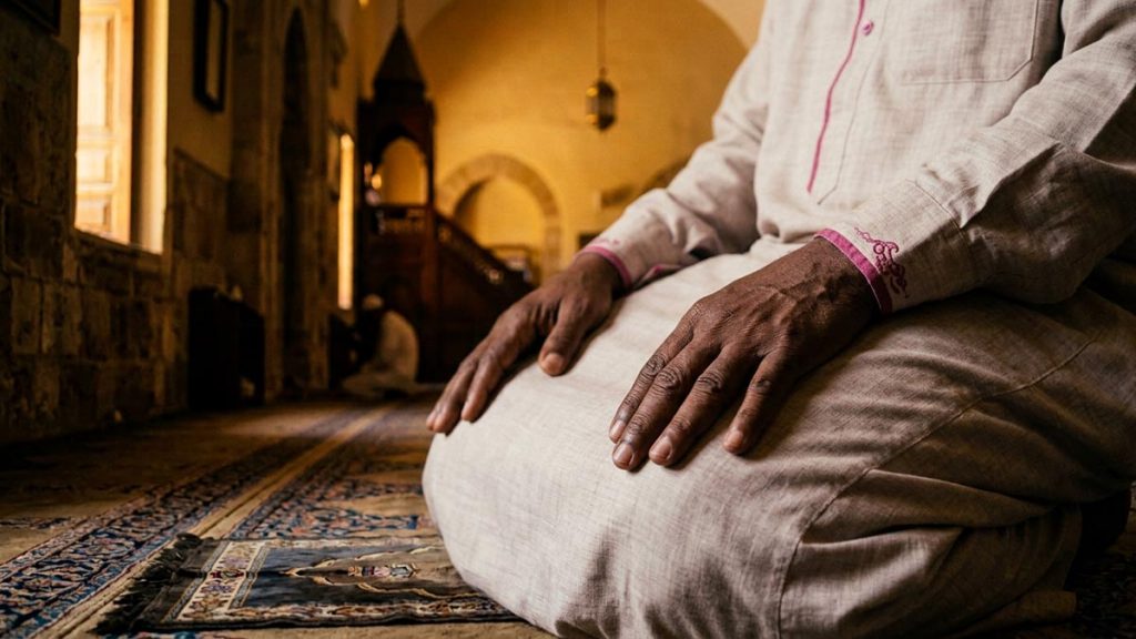 Close view of a Muslim man's hands and the open book of blessings during the Durood Ibrahim.