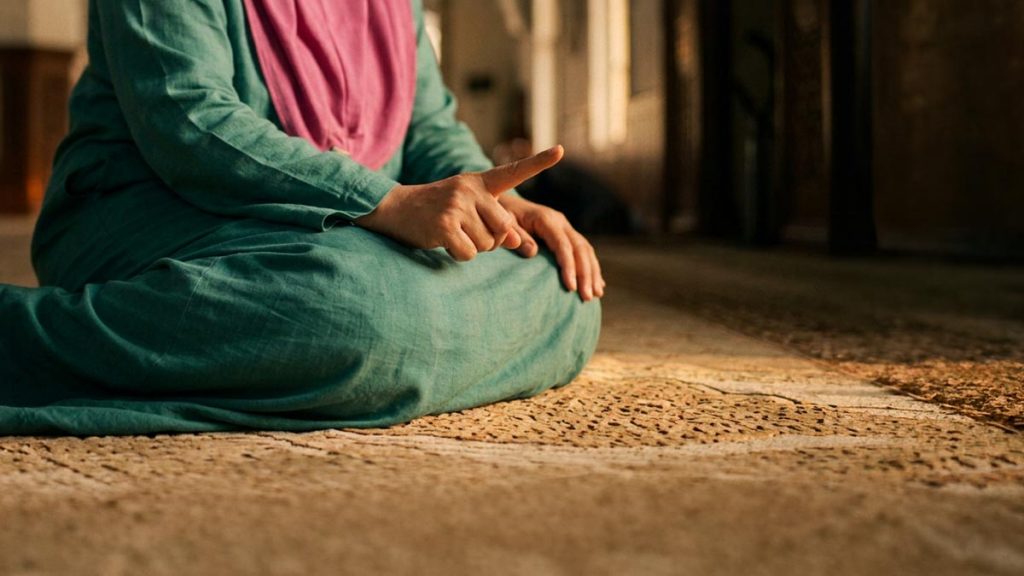 Close view of a Muslim woman's hands and the prayer mat during the Tashahhud Dua.