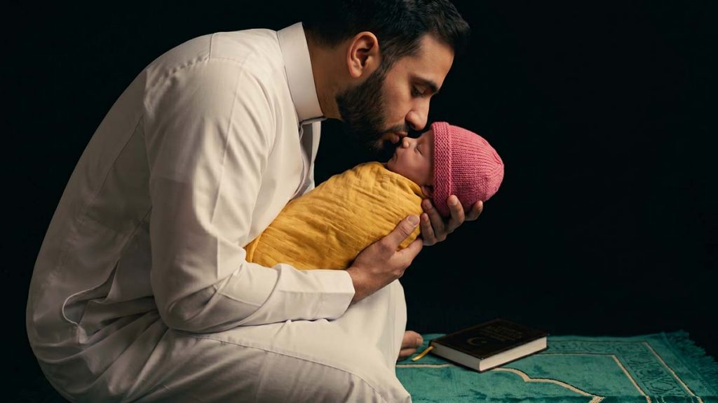 Muslim father whispering the adhan in his newborn's ear for the Naming a Baby in Islam