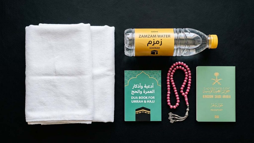 Umrah travel essentials including ihram garments and zamzam water bottle