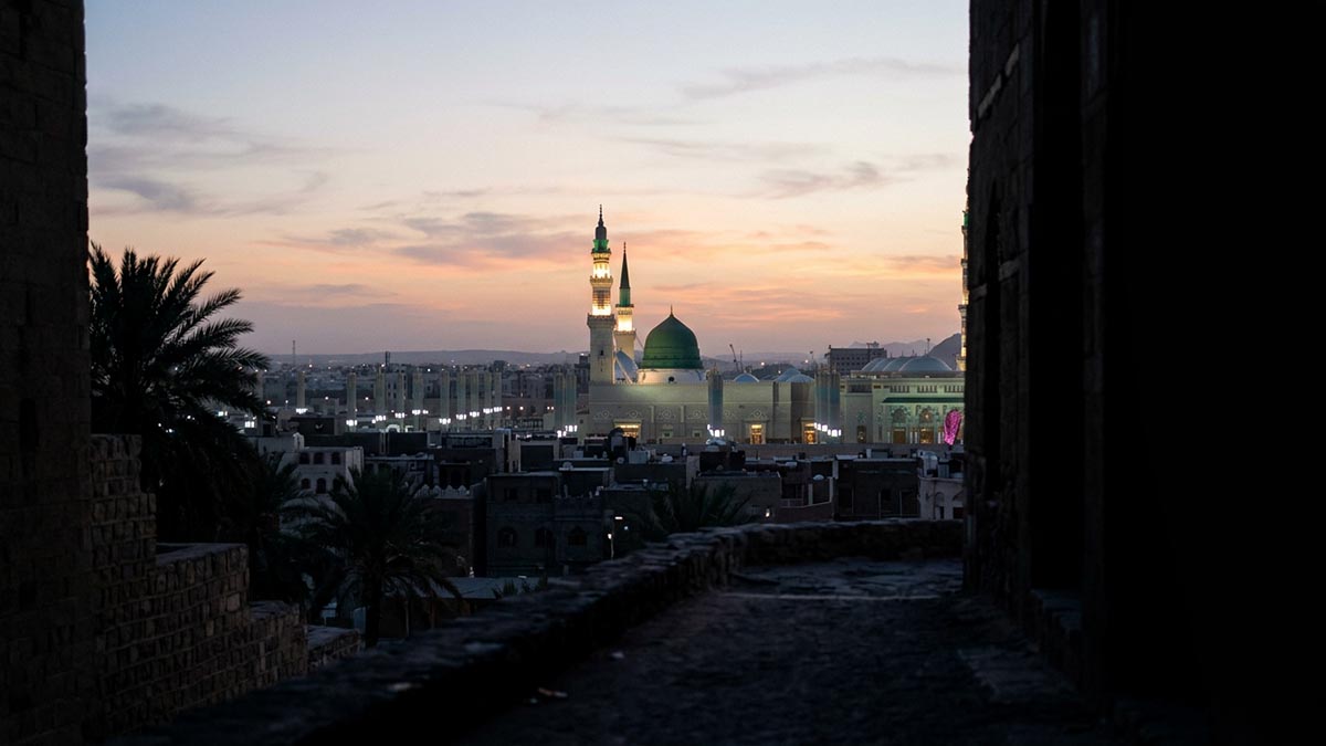 The green dome of the Prophet's Mosque against a soft dawn sky, seen from afar, no people, illustrating the meaning of Allahumma Salli Ala Muhammad.