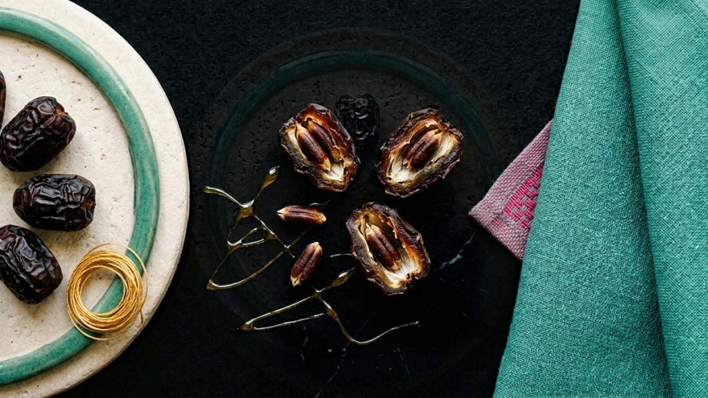 Ajwa Dates split open beside their seeds, showing their natural goodness