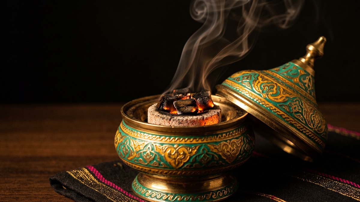 Bakhoor incense glowing in a patterned mabkhara burner with rising scented smoke