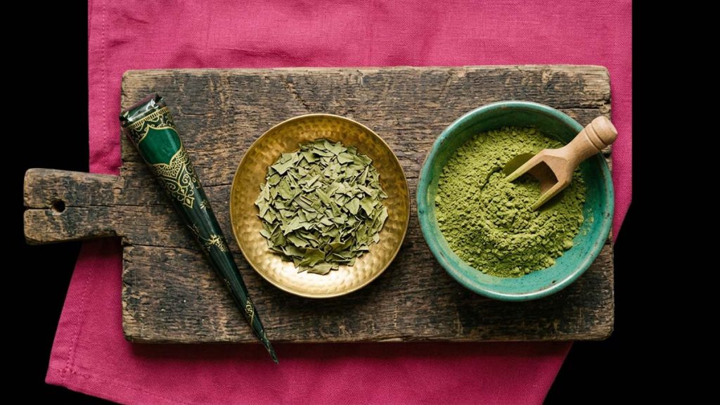 A Henna cone, powder and dried leaves arranged on a board