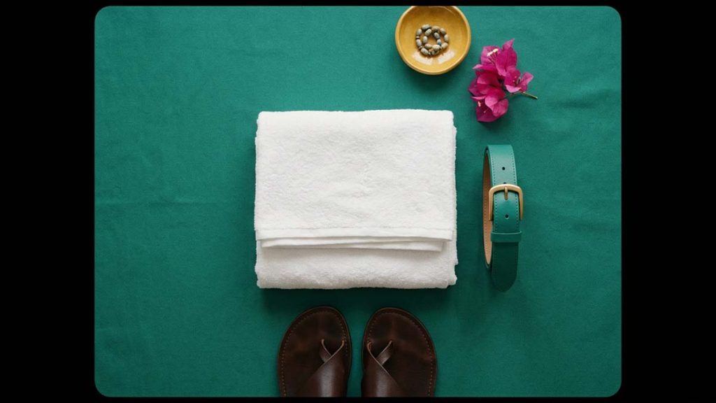 Folded white Ihram cloths with a belt and sandals laid out
