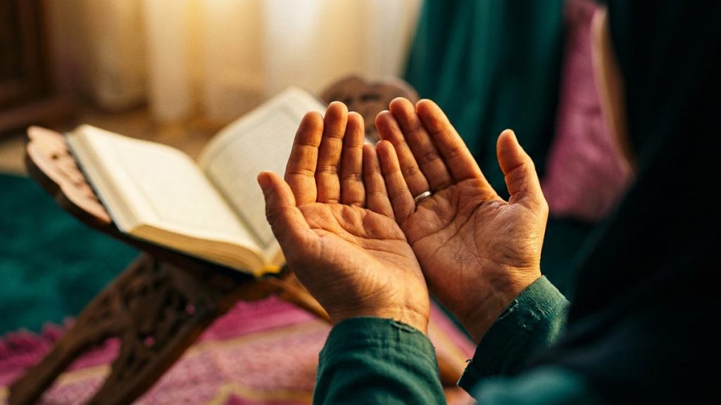 A Muslim man seated with cupped hands in quiet supplication, showing what dua means in Islam.